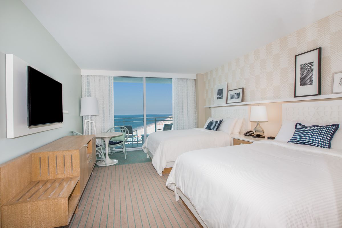 A guest room with two double beds and a view over the Gulf